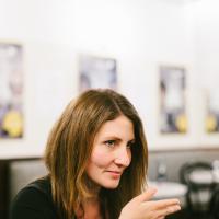 Regisseurin Jessica Bollag in einer Interviewsituation. Sie hebt die Hand und blickt konzentriert zu ihrer Interviewerein, die jedoch nicht im Bild ist.