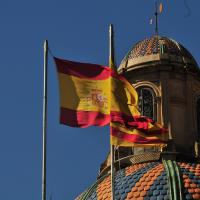 Foto einer im Wind wehenden, spanischen Flagge. Im Hintergrund eine Gebäudekuppel