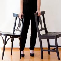 Eine Person steht zwischen zwei schwarzen Stühlen